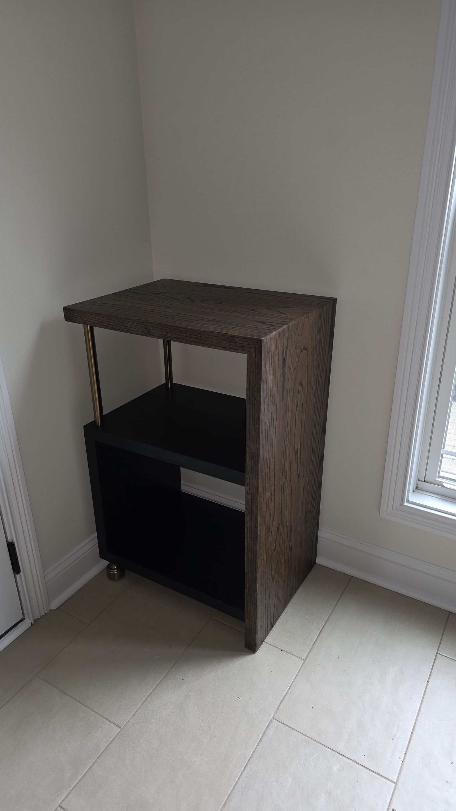 Empty red oak stereo stand with brass rod legs in the corner of a kitchen