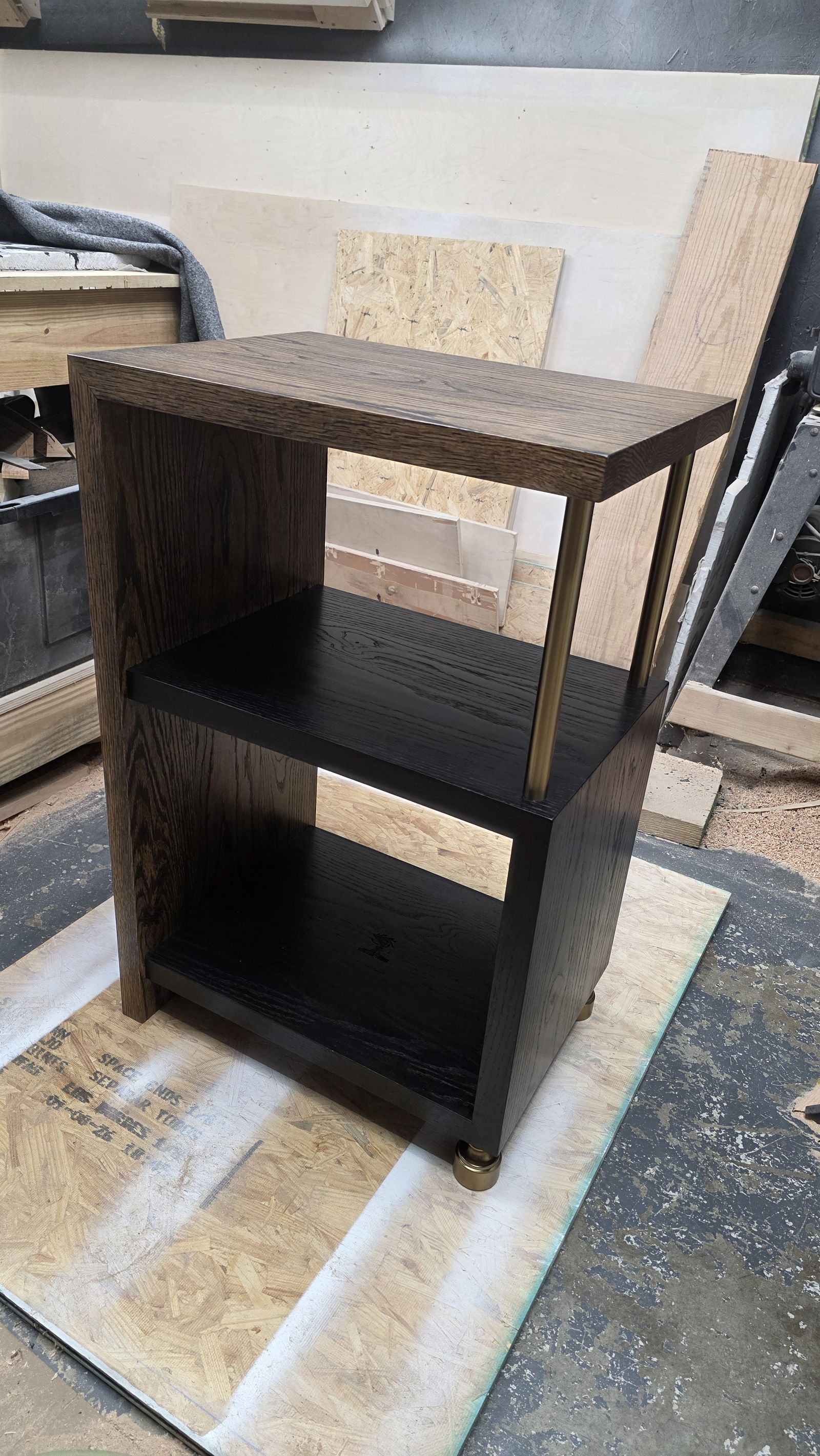Front angle of the stereo stand showing brass rod supports, brass feet, and the black painted cubby