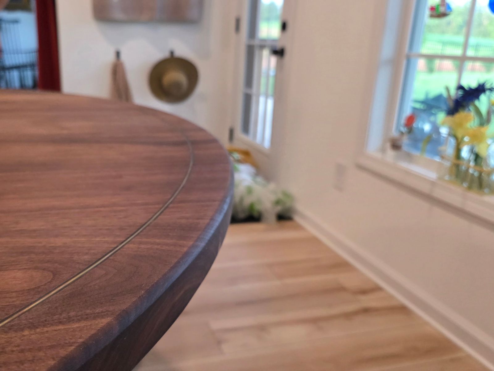 Walnut dining table edge with a thin brass inlay line running just inside the rim